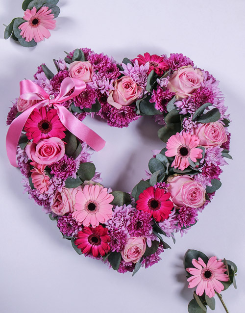 Professional studio photo of a white and red heart-shaped funeral wreath on a clean background.